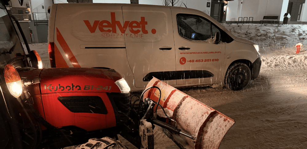 Odśnieżanie terenu osiedla zimą – traktor z pługiem i auto Velvet Sprzątanie podczas pracy w Lublinie