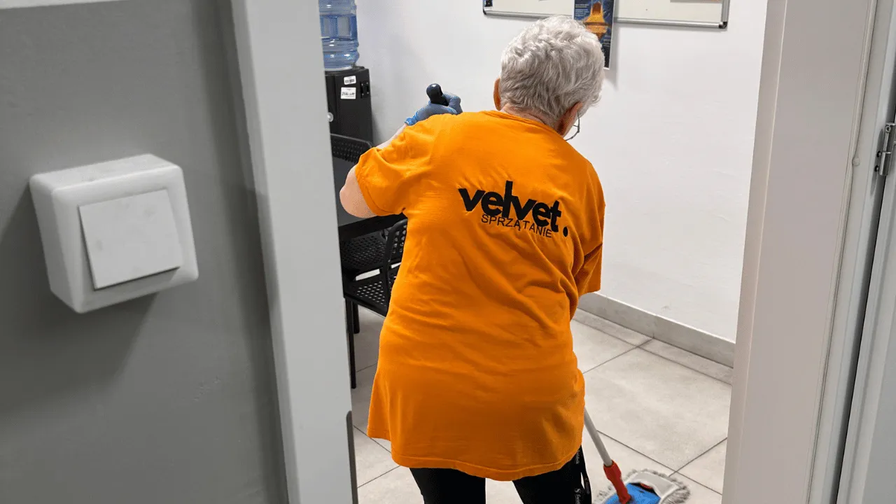 Pracownik Velvet Sprzątanie Lublin w pomarańczowej koszulce podczas sprzątania części wspólnych
