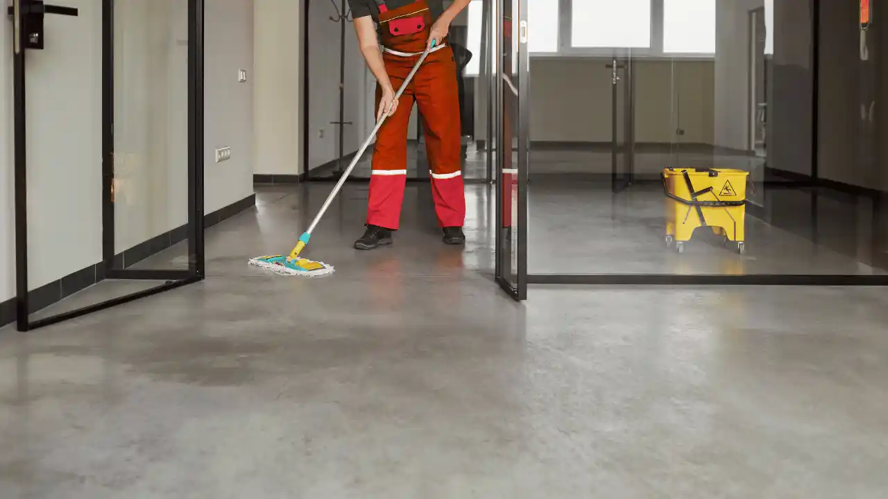 Sprzątanie stanowiska pracy w biurze - wycieranie biurka i klawiatury w rękawicach ochronnych