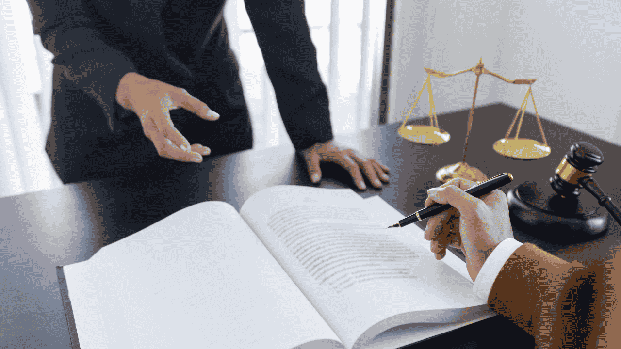 Podpisywanie umowy przy biurku – długopis, dokumenty i waga sprawiedliwości w tle