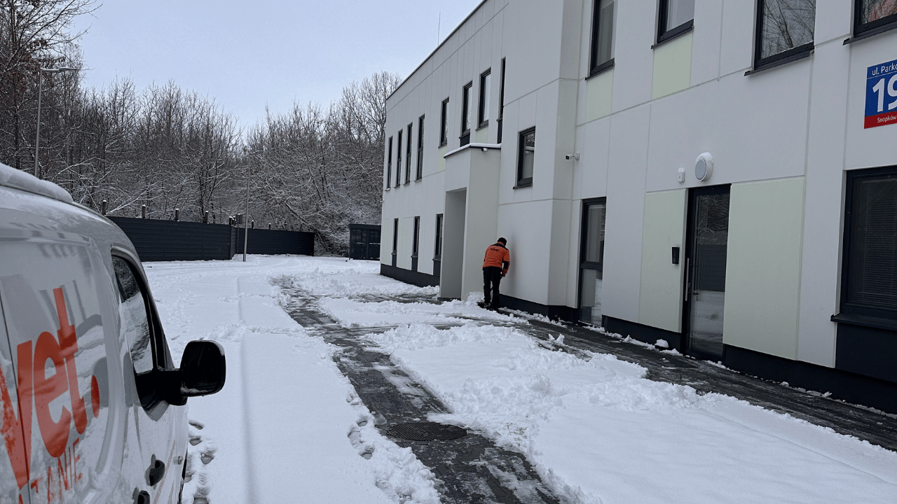 Pracownik Velvet Sprzątanie odśnieżający dojścia i chodniki przy budynku firmowym